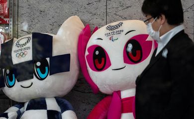 A man wearing a protective face mask, following an outbreak of the coronavirus disease (COVID-19), walks past Tokyo 2020 Olympic Games mascot Miraitowa and Paralympic mascot Someity plushies at a building in Tokyo