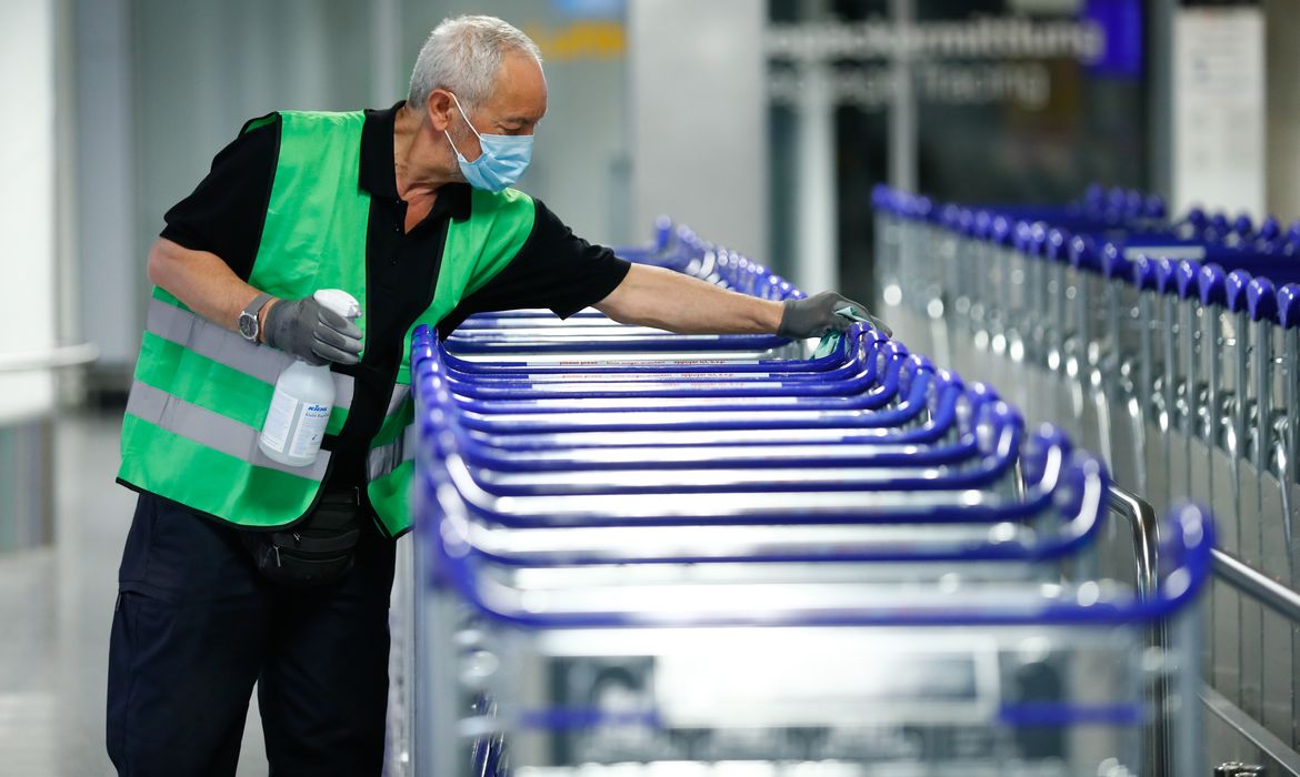 Funcionário desinfeta carrinhos em aeroporto de Frankfurt