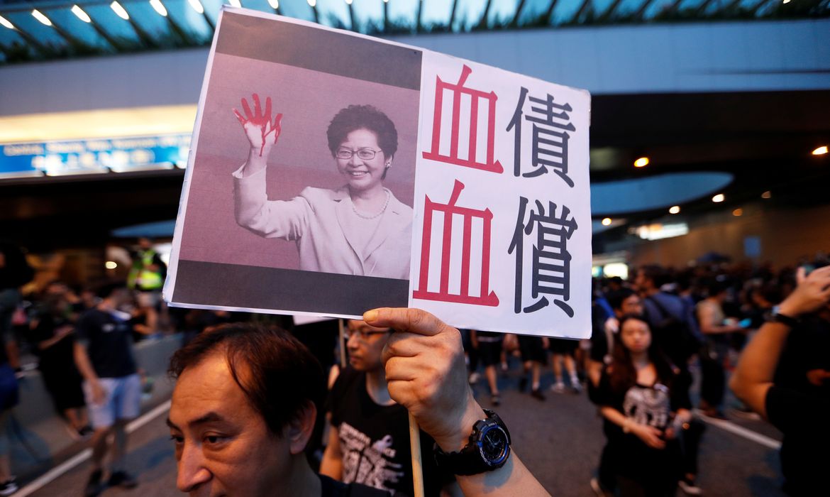 Um manifestante segura um cartaz representando a executiva-chefe de Hong Kong, Carrie Lam, durante uma manifestação exigindo que os líderes de Hong Kong renunciem e retirem o projeto de extradição, em Hong Kong, China, em 16 de junho de 2019.