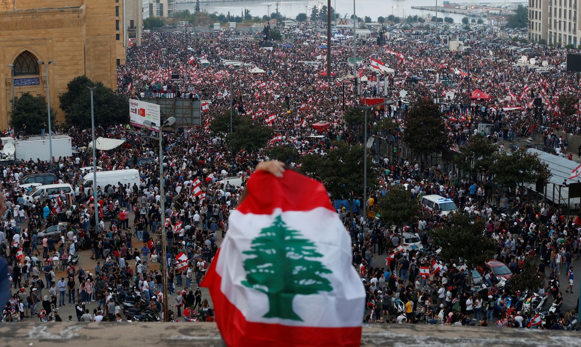 Manifestantes carregam bandeiras nacionais durante um protesto contra o governo no centro de Beirute, Líbano, em 20 de outubro de 2019