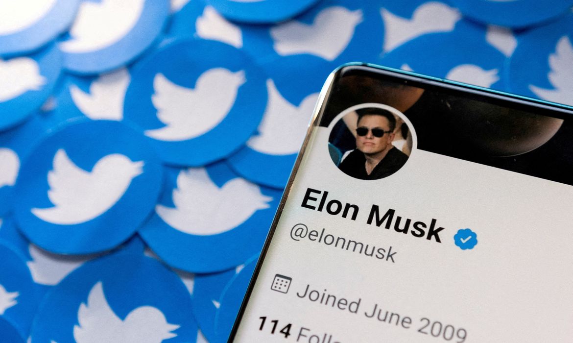 .Perfil do Twitter de Elon Musk em um smartphone junto a logotipos impressos do Twitter.