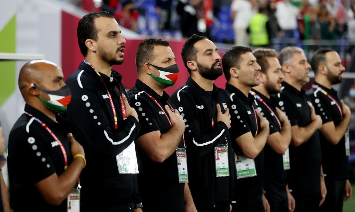 Comissão técnica da seleção da Palestina canta hino nacional antes de partida contra a Jordânia pela Copa Árabe
07/12/2021 REUTERS/Ibraheem Al Omari