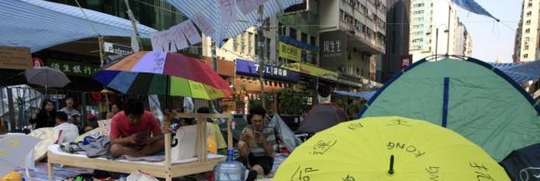 Protestantes pró-democracia descansam durante protesto por mais participação política que fechou ruas de Hong Kong, na China