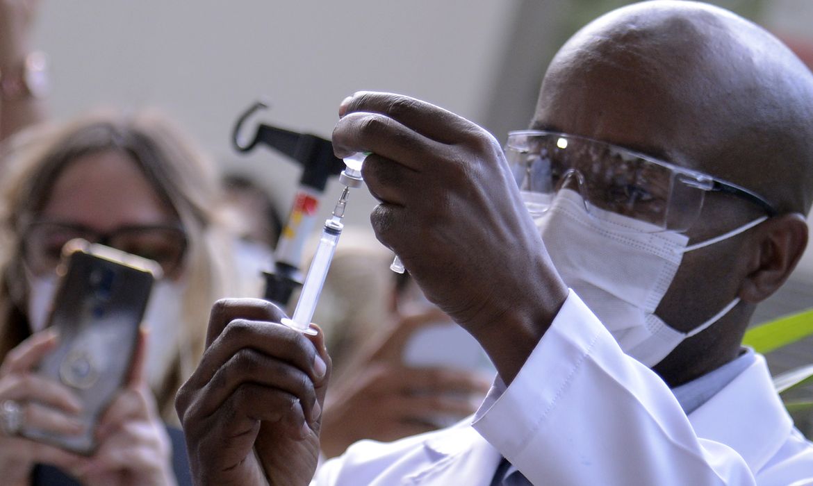 Servidor da Fiocruz prepara vacina de Oxford/AstraZeneca para a primeira aplicação no Brasil.
