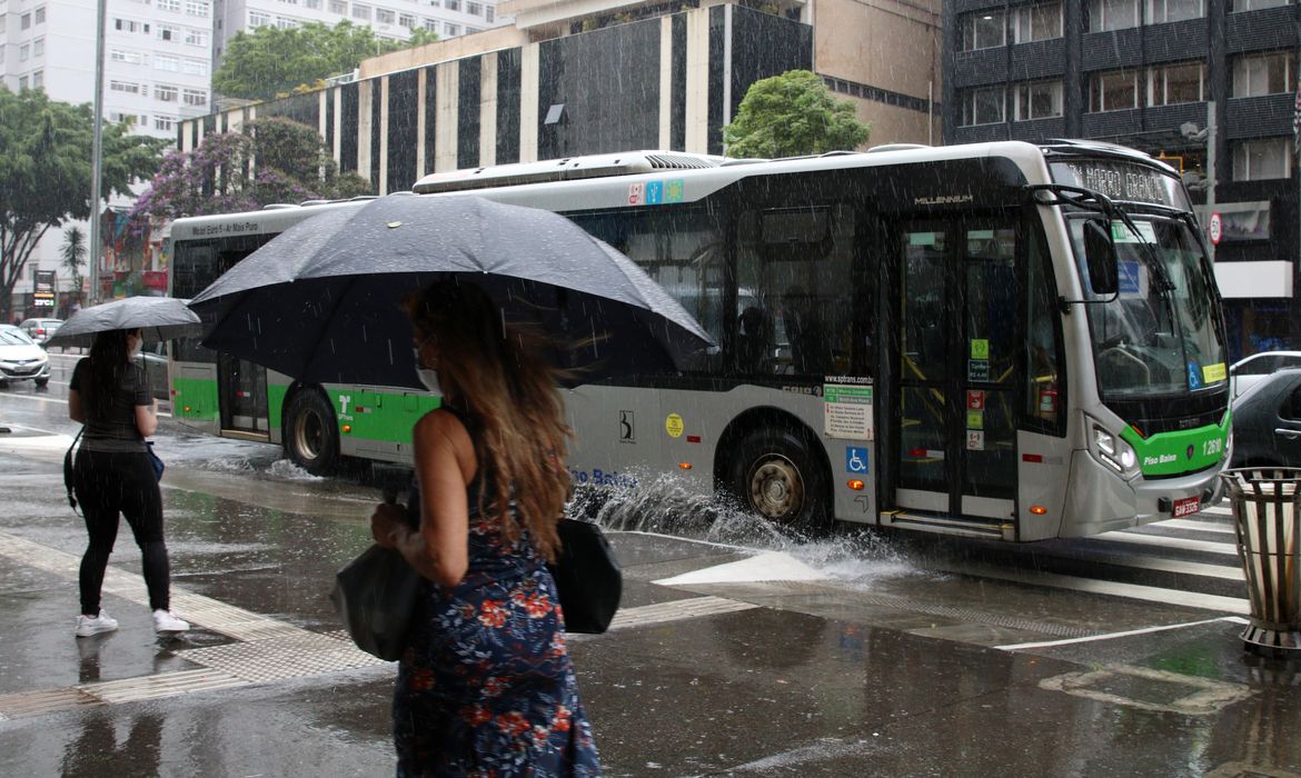 Ônibus joga água na calçada durante chuva na Avenida Paulista.