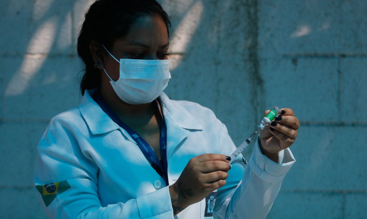 A técnica de enfermagem, Paula Roberta Moreira mostra a ampola da vacina contra a covid-19 antes de aplicar a injeção.