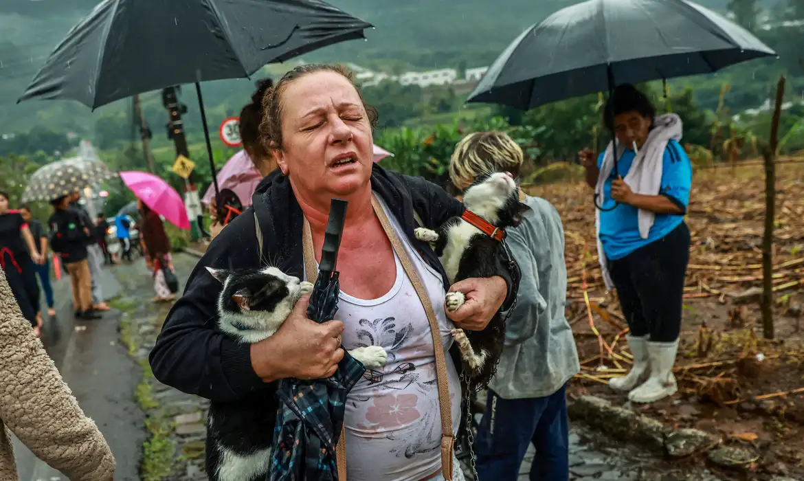 Una mujer reacciona mientras camina con dos gatos rescatados durante las fuertes lluvias en Encantado, estado de Rio Grande do Sul, Brasil, 2 de mayo de 2024. REUTERS/Diego Vara