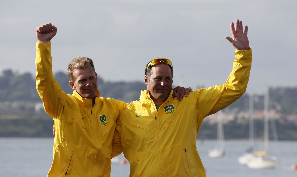 Bronze medallists Brazil's skipper Robert Scheidt and crew Bruno Prada wave during their men's star class keelboat sailing medal race victory ceremony at the London 2012 Olympic Games in Weymouth and Portland
