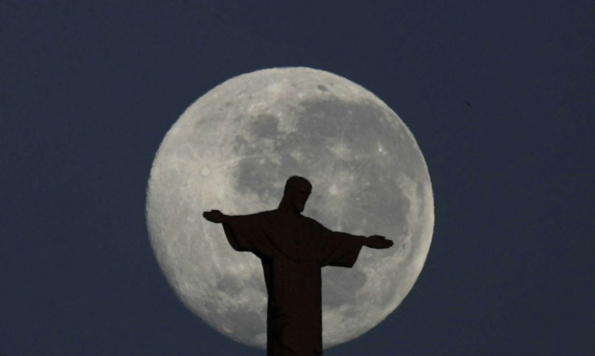 A lua cheia brilha atrás da estátua do Cristo Redentor no Rio de Janeiro