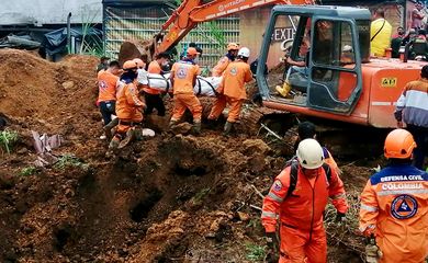 Colombian Civil Defense workers unearth the body of a deceased person in a landslide that was caused by heavy rains in the country, in Mallana