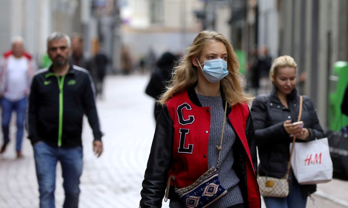 Pessoas com e sem máscara de proteção caminham em rua de Amsterdã