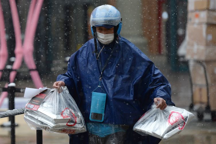 Ele.me deliveryman wearing a face mask delivers food amid snowfall on Valentine's Day in Beijing