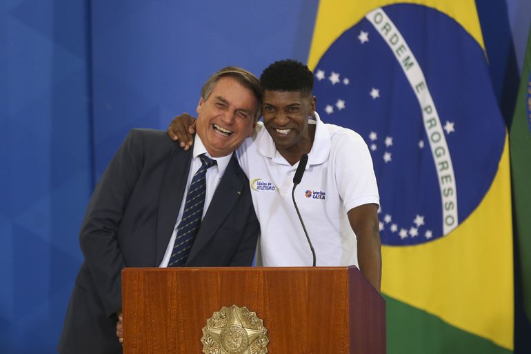 O presidente Jair Bolsonaro, e o atleta, André Domingos, durante a  solenidade de assinatura do projeto de lei que institui o Plano Nacional do Desporto (PND), no Palácio do Planalto