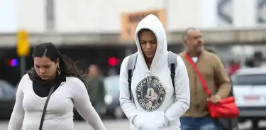 Pessoas agasalhadas caminham na rua