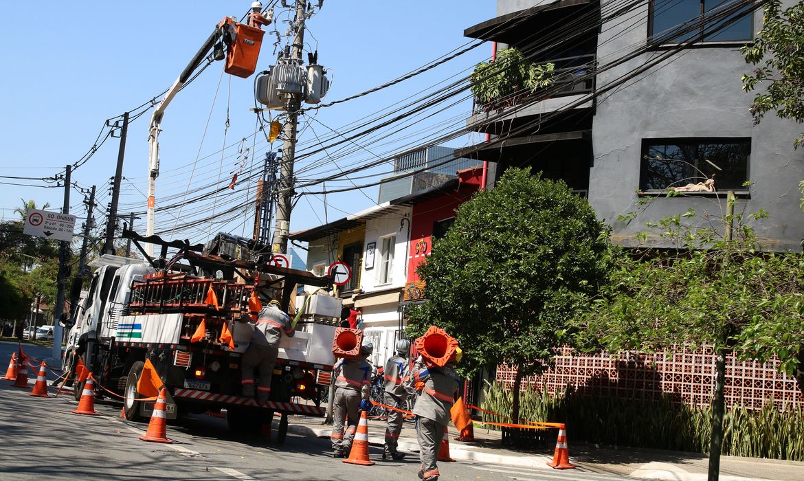 Funcionários da Enel fazem manutenção em poste de energia elétrica no bairro de Pinheiros.