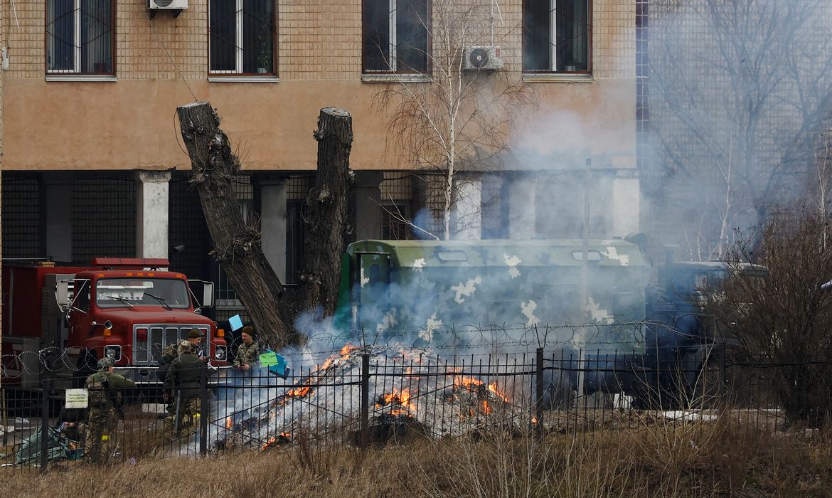 Uniformed people throw items into a fire outside an intelligence building on the premises of the Ukrainian Defence Ministry's unit, in Kyiv
