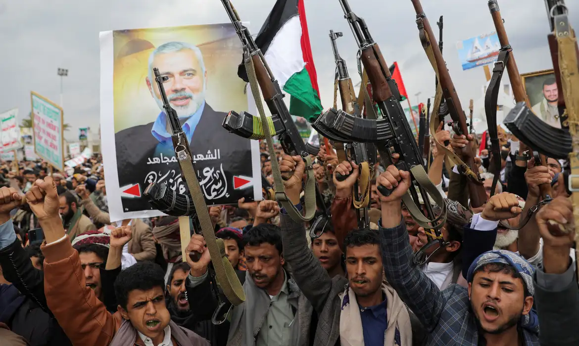 Protesters, mainly Houthi supporters, hold firearms next to a poster of assassinated Hamas chief Ismail Haniyeh, at the rally to show solidarity with Palestinians in the Gaza Strip, in Sanaa, Yemen, August 2, 2024. REUTERS/Khaled Abdullah