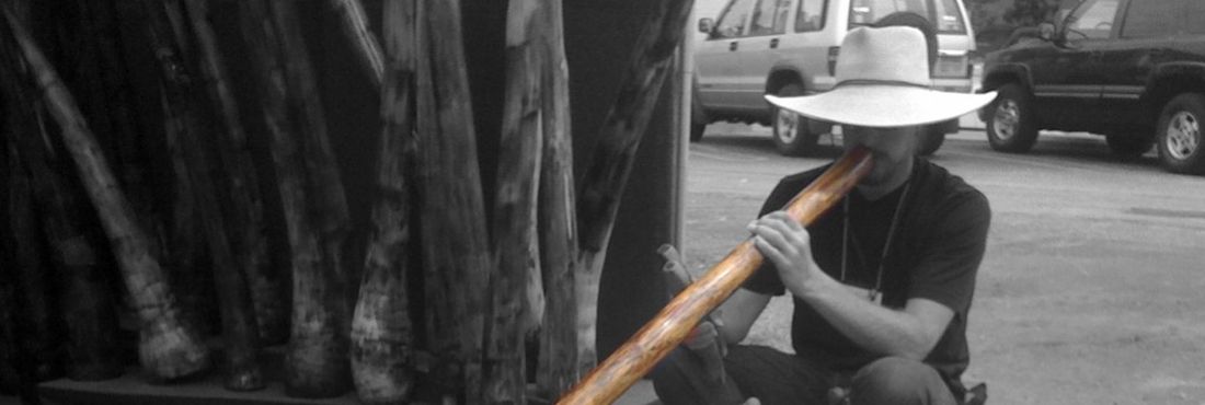 Homem tocando didjeridu, instrumento de origem australiana