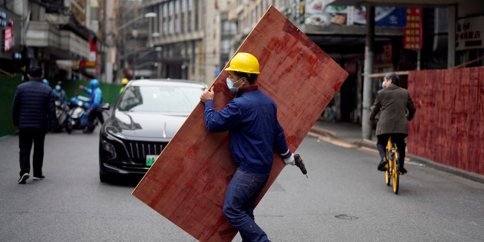 Funcionário monta barreiras em rua de Xangai para criar área isolada durante lockdown da Covid-19