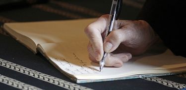 Mão de idoso escreve em caderno