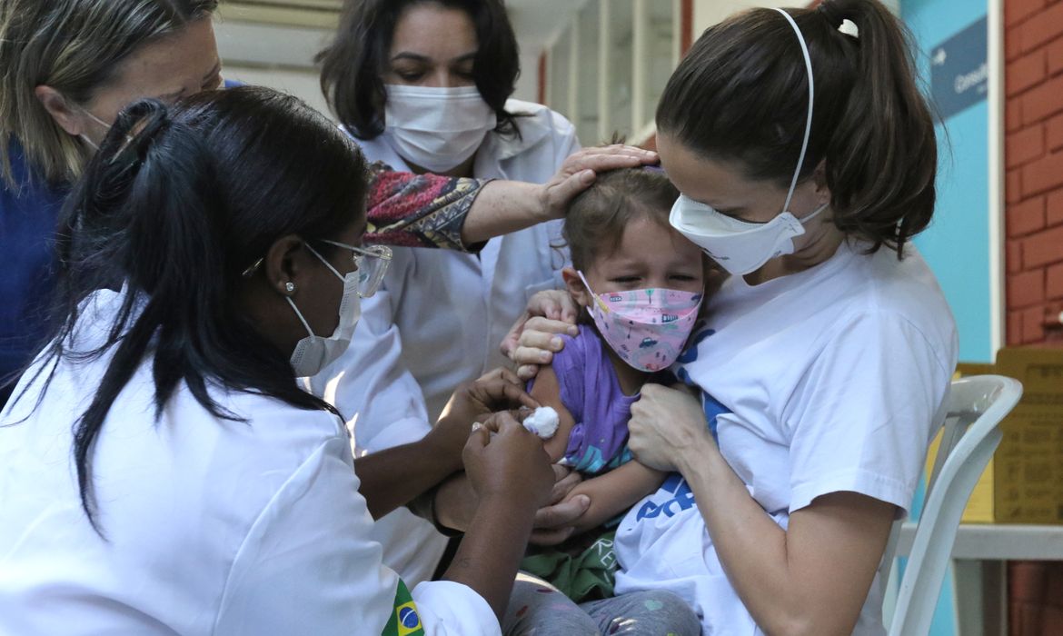 A menina Clarice Moretti, 4 anos, toma sua primeira dose de vacina contra a Covid-19 no Centro Municipal de Saúde Píndaro de Carvalho Rodrigues, na Gávea, zona sul da cidade.