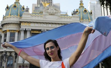 A cantora lírica e pianista Vivian Fróes, mulher trans, posa com bandeira em frente ao Theatro Municipal, na Cinelândia.  
