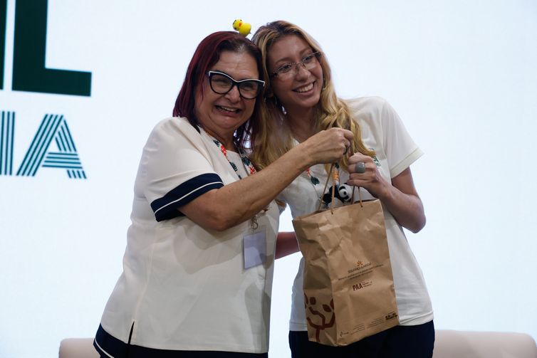 Belém (PA), 17/11/2025 - A voluntaria Gabriella Araujo, recebe o kit durante ato de entrega simbólica dos kits da Agricultura Familiar (PAA) para os voluntários da COP30, no Pavilhão Brasil. Foto: Tânia Rêgo/Agência Brasil