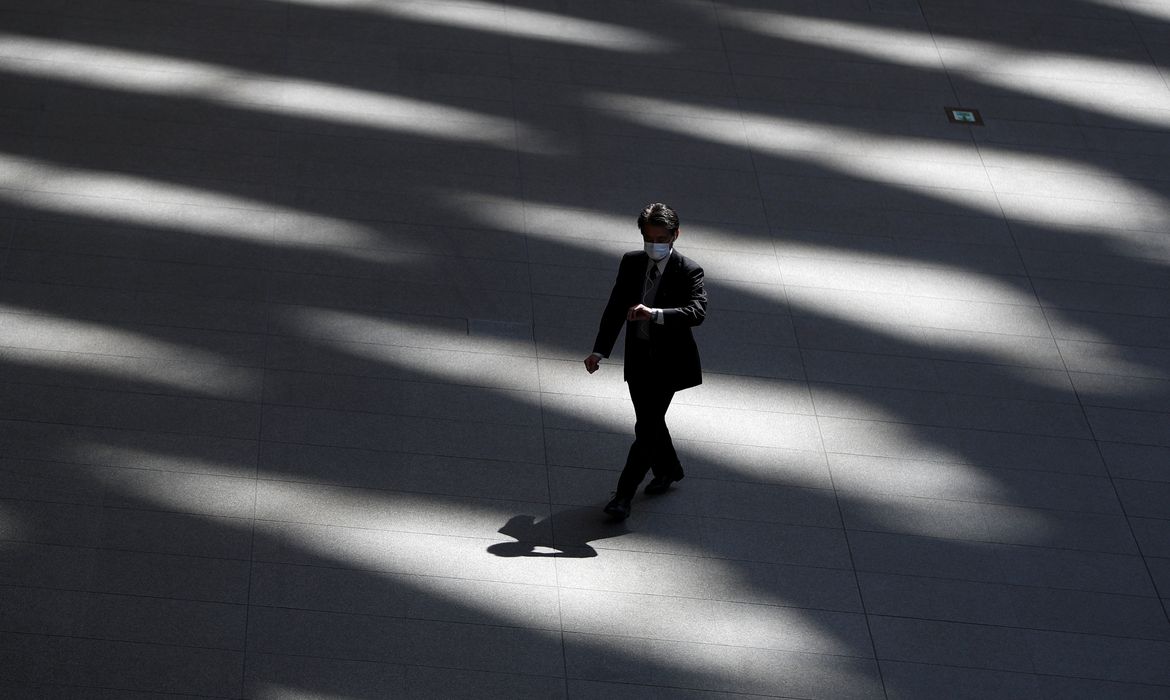 A man wearing a protective face mask, following an outbreak of the coronavirus disease, walks past inside an almost empty convention complex in Tokyo, Japan