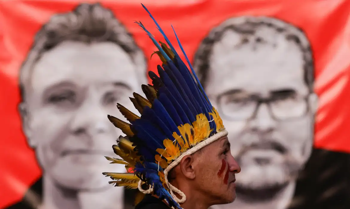 Manifestante em frente a imagem de jornalista britânico Dom Phillips e de indigenista Bruno Pereira em Brasília