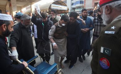 Homens transportam vítima ferida em ataque suicida a mesquita em Peshawar, no Paquistão