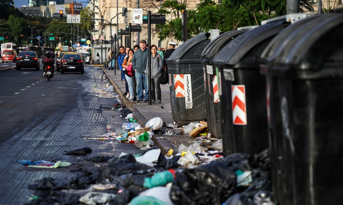 People stand at a bus stop near garbage on the ground, during a 24-hour general strike against the adjustment policy of Argentinian President Javier Milei's government, in Buenos Aires, Argentina April 10, 2025. Reuters/Agustin Marcarian/Proibida reprodução