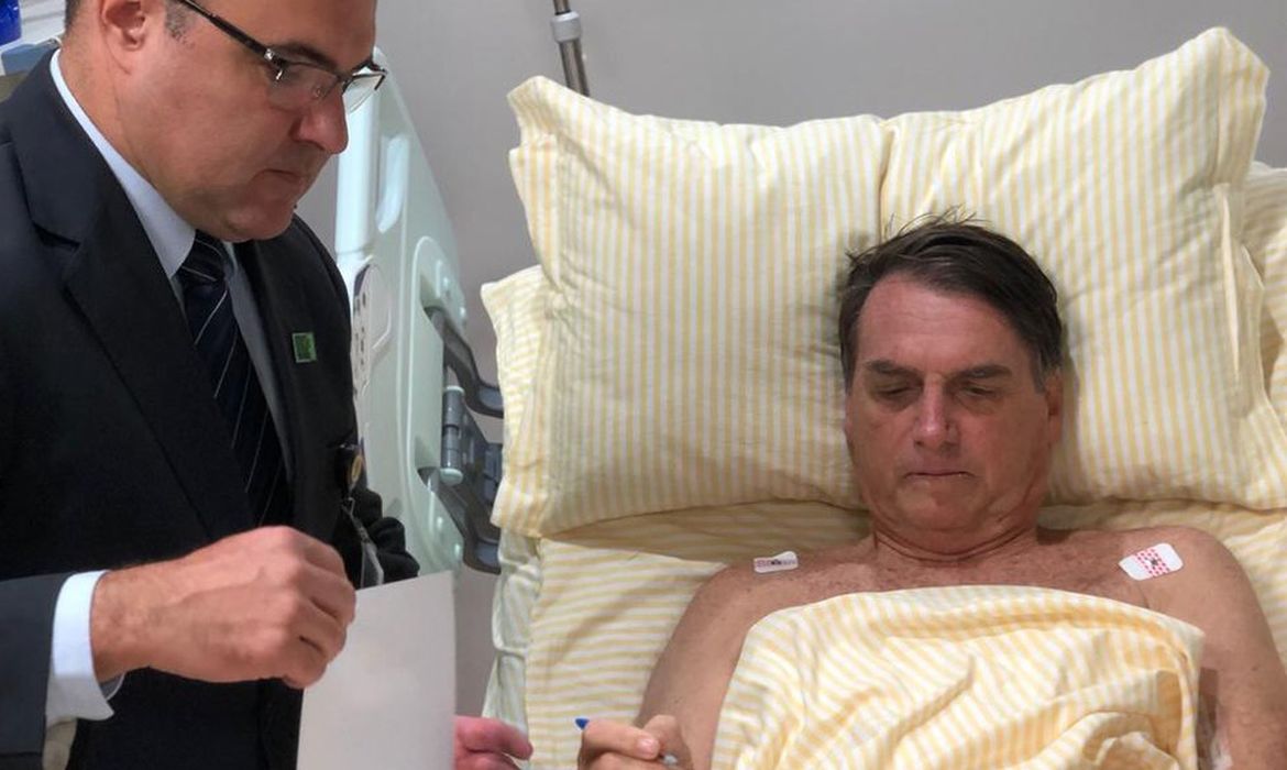 O presidente Jair Bolsonaro assina decretos no hospital 