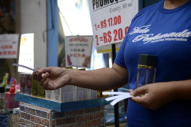 Salesperson hands out fragrances to pedestrians in a store in the traditional Sahara shopping area, in the center of Rio de Janeiro