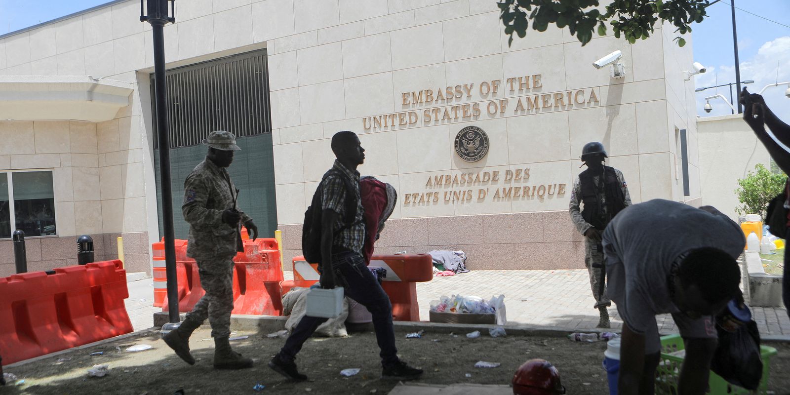Homem carrega seus pertences após polícia usar gás lacrimogêneo para dispersar pessoas acampadas em frente à embaixada dos Estados Unidos em Porto Príncipe, no Haiti
