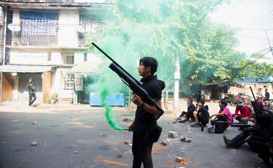 Manifestante segura arma caseira feita com canos durante protesto contra golpe militar em Mianmar