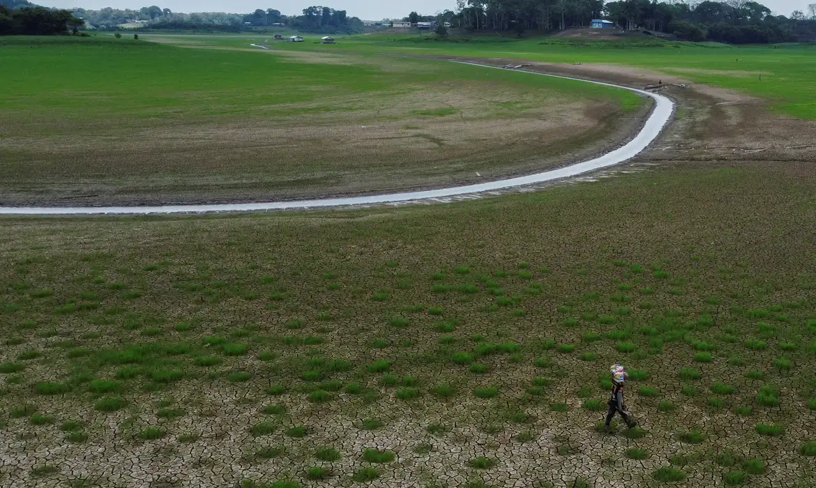 A man carries food in a dry area near the Parana do Manaquiri stream, which flows into the Solimoes river, as the region is hit by a severe drought in Manaquiri, Amazonas state, Brazil, October 21, 2023. REUTERS/Suamy Beydoun