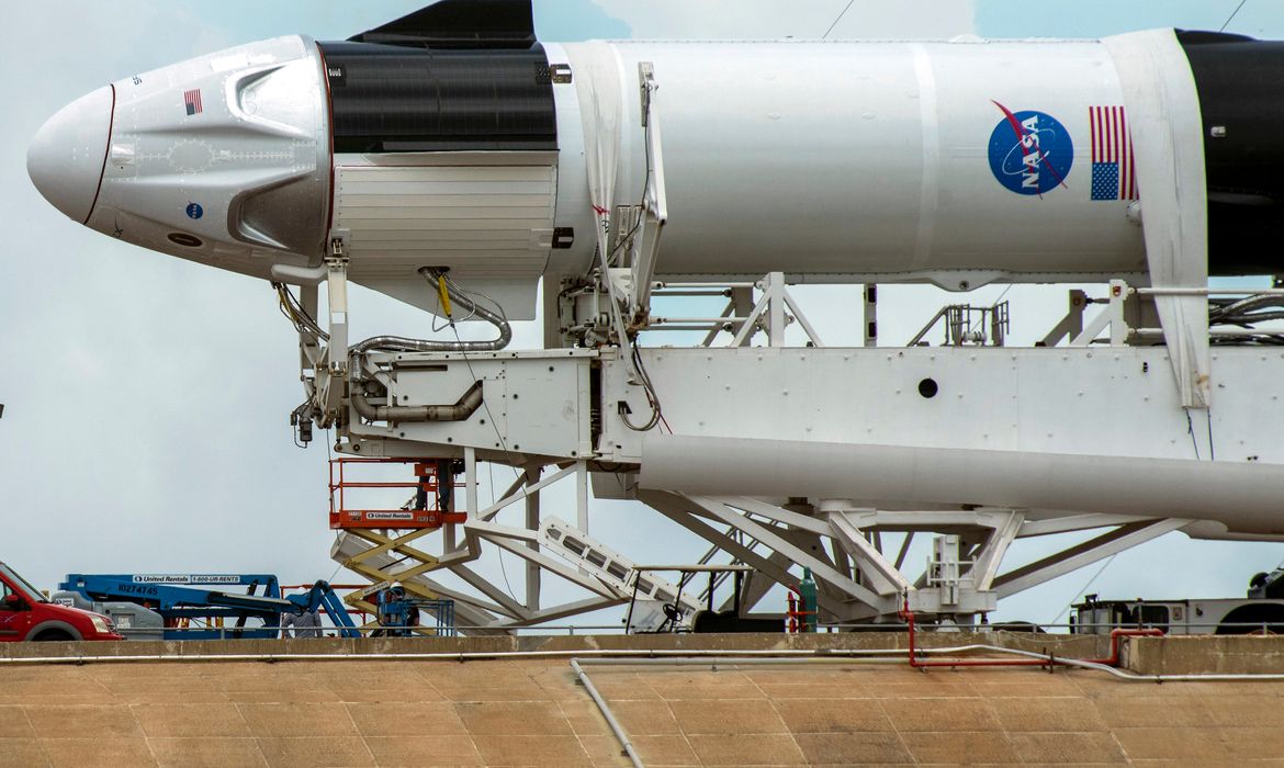 Crews work on the SpaceX Crew Dragon, attached to a Falcon 9 booster rocket, as it sits horizontal on Pad39A