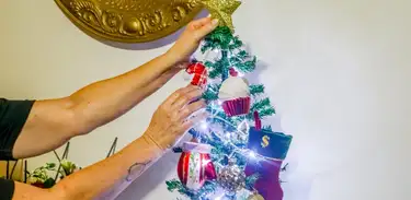 Mulher decora árvore de Natal com luminárias elétricas