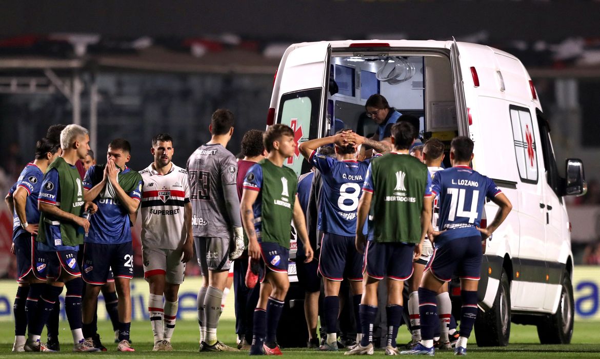 Jogadores de Nacional e São Paulo acompanham atendimento ao zagueiro Juan Izquierdo, do Nacional, após entrada de ambulância no gramado durante partida entre as duas equipes pela Copa Libertadores em São Paulo
22/08/2024 REUTERS/Carla Carniel