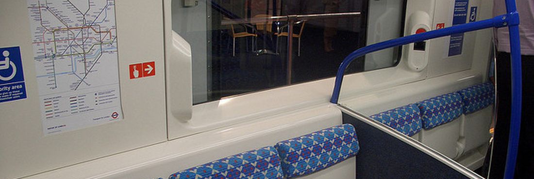 Vagão do metrô londrino, com assentos retráteis e barra de sustentação, destina espaço para até dois cadeirantes