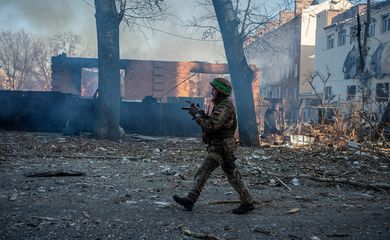 Soldado ucraniano caminha em frente a prédio em chamas na cidade de Bakhmut, na linha de frente da guerra