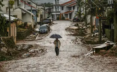 A man with an umbrella walks along a partially destroyed street after floods in Mucum, Rio Grande do Sul state, Brazil May 11, 2024. REUTERS/Adriano Machado