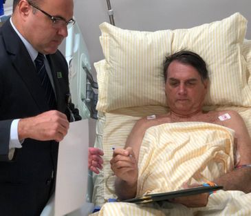 O presidente Jair Bolsonaro assina decretos no hospital 