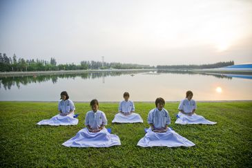 Crianças meditam em frente a lago