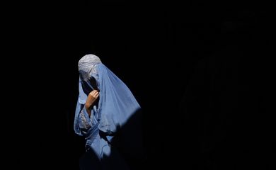 A burqa-clad Afghan woman walks in an old bazaar in Kabul