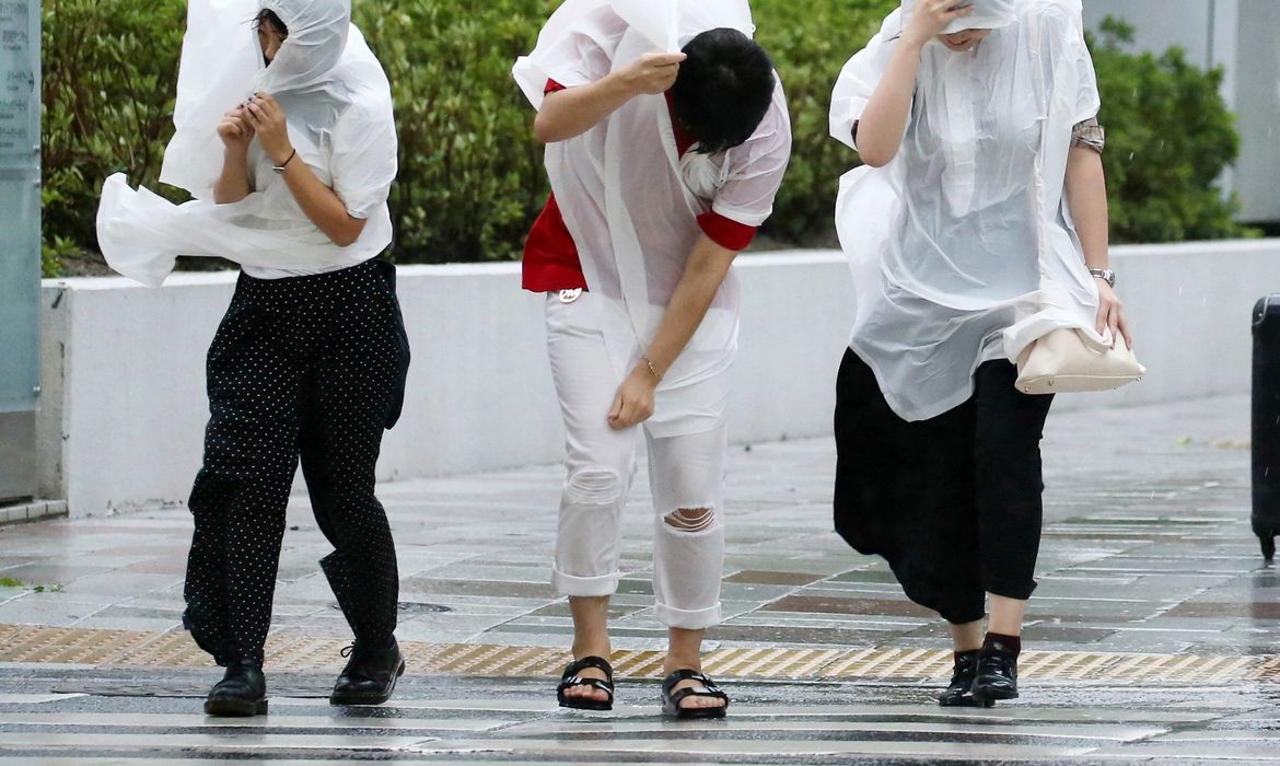 Osaka – Transeuntes caminham com dificuldade em meio a fortes rajadas de vento e chuvas provocadas pelo tufão Jebi