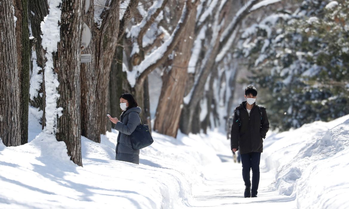 Passersby wearing protective masks walk on a snow-covered street in Sapporo, Hokkaido