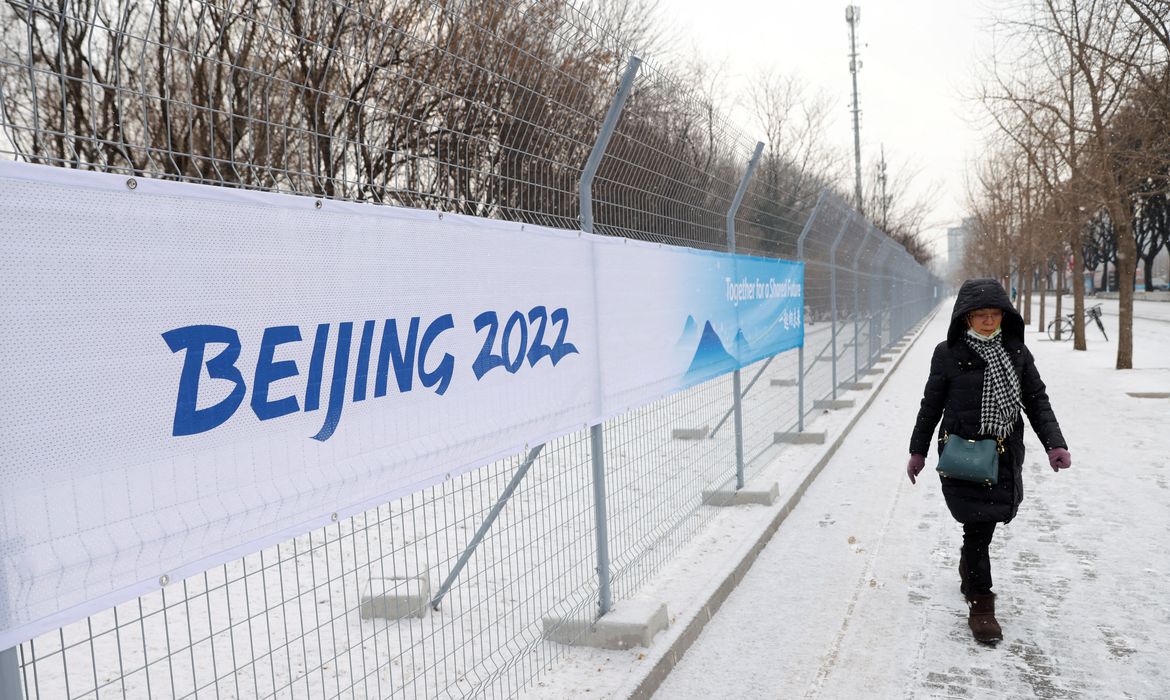 Pedestre caminha ao lado de cerca que a separa da bolha de isolamento da Olimpíada de Inverno de Pequim 2022 - Jogos de Inverno - Beijing - neve