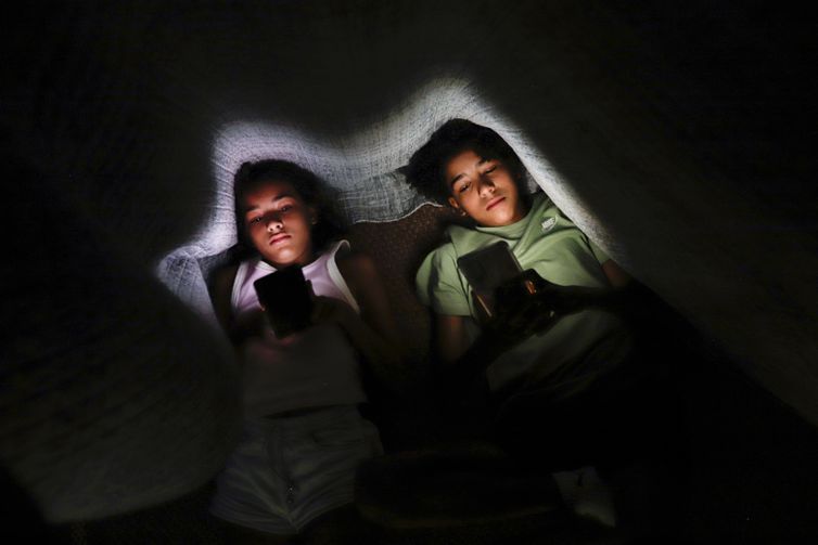 Brasília (DF) 28/01/2025 - Os irmãos Clara Santana (10) e Pedro Santana (13), são vistos com celular na mão embaixo de um cobertor.
Uma a cada 3 crianças tem perfil aberto em redes, alerta pesquisa
Dados foram divulgados nesta terça pela Unico e Instituto Locomotiva
Foto: Joédson Alves/Agência Brasil