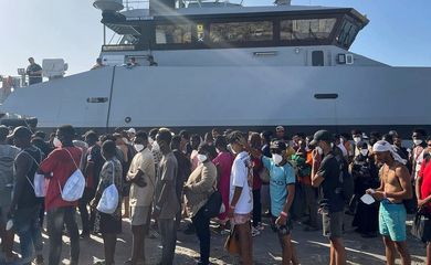 Migrantes recém chegados aguardam no porto da ilha de Lampedusa, na Italia